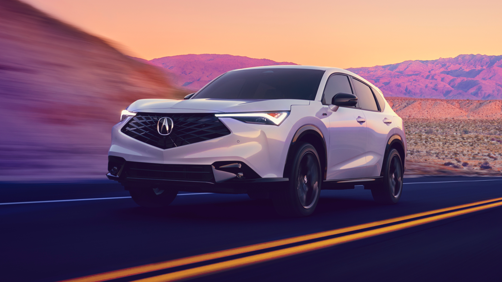 Front-view of a grey Acura ADX on a mountain road with a purple light treatment  on the mountains. 