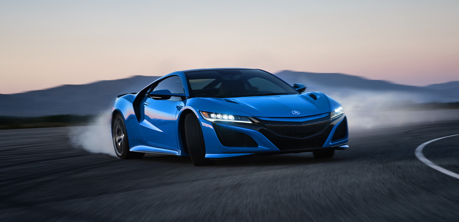 A blue Acura NSX rounding the corner on a racetrack.